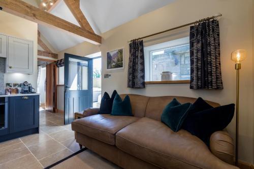 a living room with a brown couch with blue pillows at Country Cottage with Hot Tub - pre-heated for your arrival in Buxton