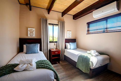 a bedroom with two beds and a window at Arebbusch Travel Lodge in Windhoek