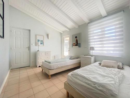 une chambre blanche avec deux lits et une fenêtre dans l'établissement Flocon de Sel, à Sainte-Marie de Ré