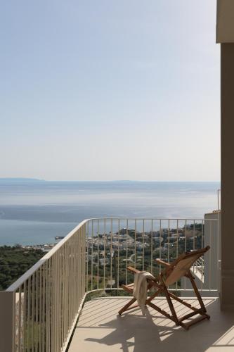 a wooden chair sitting on a balcony overlooking the ocean at Stella in the Village Studios in Plakias