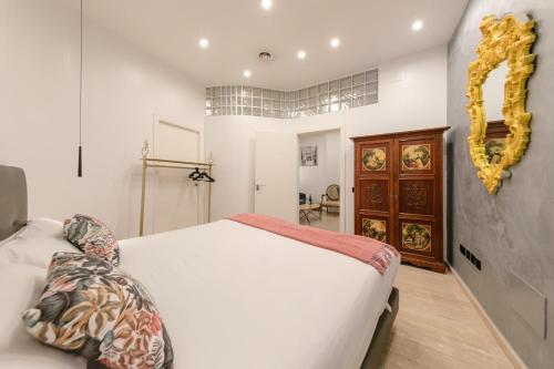 Un dormitorio con una cama blanca y un espejo dorado. en Guadalquivir, en Sevilla