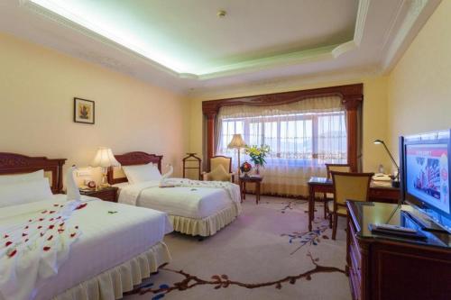 a hotel room with two beds and a flat screen tv at Quanzhou Hotel in Quanzhou