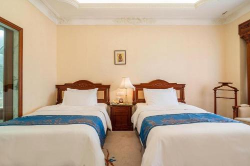 a bedroom with two beds and a lamp at Quanzhou Hotel in Quanzhou