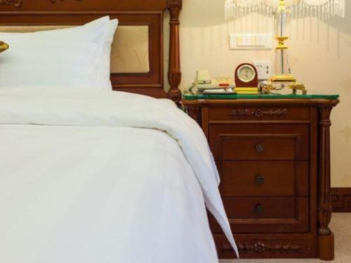 a bedroom with a bed and a dresser with a clock at Quanzhou Hotel in Quanzhou