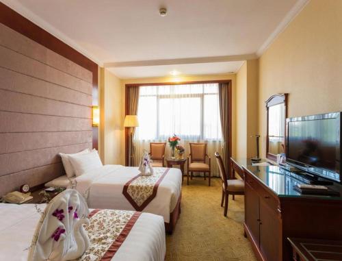 a hotel room with two beds and a flat screen tv at Quanzhou Hotel in Quanzhou