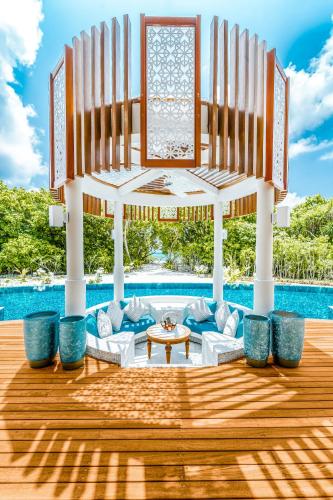 a pavilion with chairs and a table in front of a pool at Hideaway Beach Resort & Spa, FREE SHARED CHARTER FLIGHT for two on stays of 7 or more nights from September 2025 until 23rd December 2026 in Dhidhdhoo