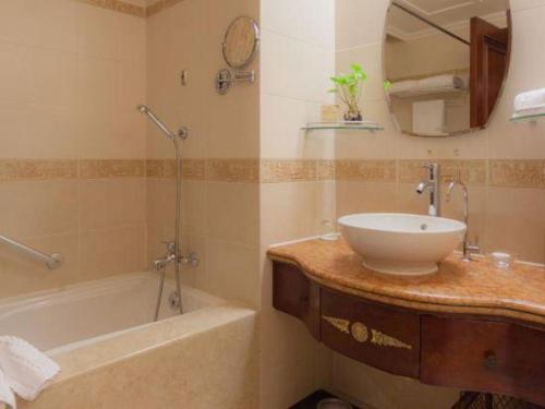 a bathroom with a sink and a tub and a mirror at Quanzhou Hotel in Quanzhou
