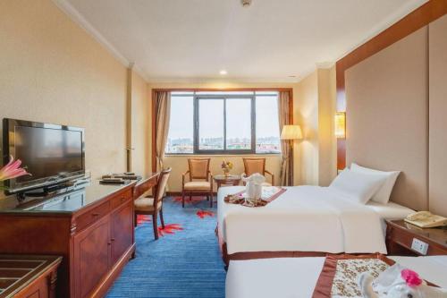 a hotel room with two beds and a flat screen tv at Quanzhou Hotel in Quanzhou