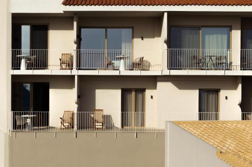 a building with chairs and tables on the balcony at Stella in the Village Studios in Plakias