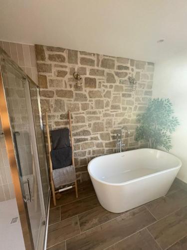 a bath tub in a bathroom with a stone wall at Teach Annie in Annagry
