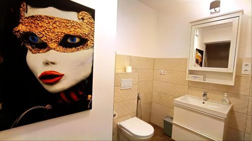 a bathroom with a painting of a woman with a mask at Studio Fortuna Park Residence in Sfântu-Gheorghe