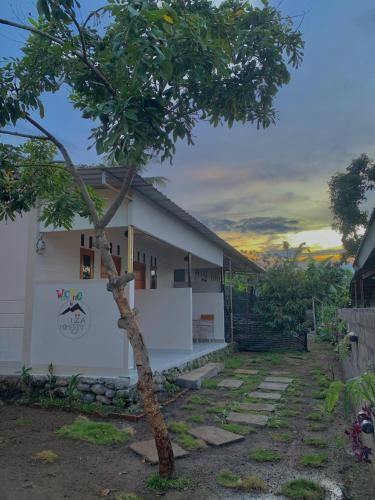 a house with a tree in front of it at Iza home stay in Senaru