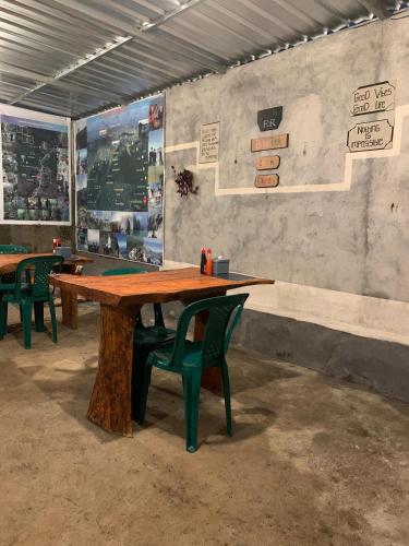 a large wooden table with green chairs in a room at Iza home stay in Senaru