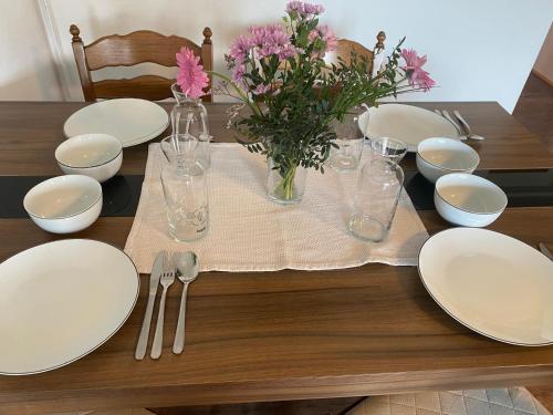 a wooden table with white plates and flowers on it at Haus Kampl - Appartement Grundlsee in Bad Mitterndorf