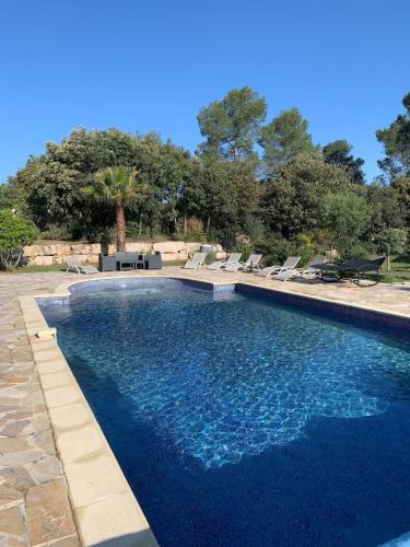 une piscine avec de l'eau bleue dans une cour dans l'établissement L'Hacienda - Villa Climatisée avec Piscine, à Lorgues