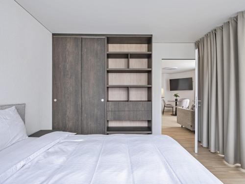 ein Schlafzimmer mit einem großen weißen Bett und ein Wohnzimmer in der Unterkunft MOOI Apartments Grenchen in Grenchen