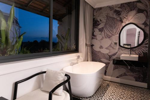a bathroom with a tub and a sink and a mirror at The City Boutique Hotel in Bien Hoa