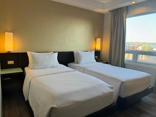 two beds in a hotel room with a window at Circle Inn - Iloilo City Center in Iloilo City