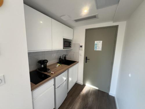 a kitchen with white cabinets and a sink and a door at Résidence Claire Roman in Valence