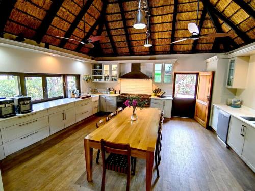 Una gran cocina con una mesa y sillas de madera. en Buccara Waterberg - Molapo, en Lephalale