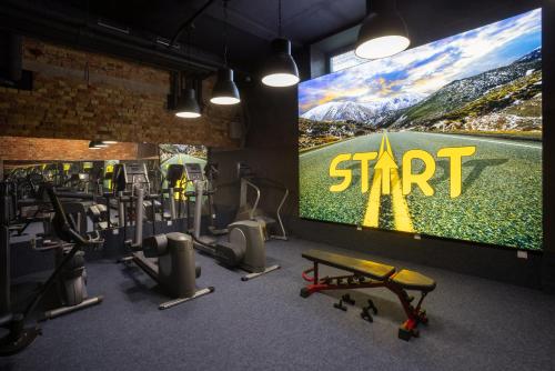 a gym with a large screen with the word start at R73 Residences in Pécs