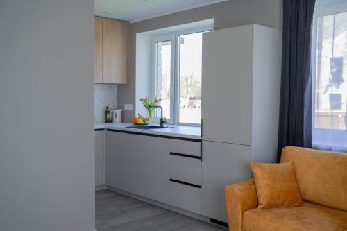 a kitchen with white cabinets and a chair next to a window at Rahukodu in Kõrgessaare