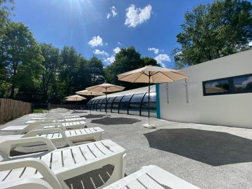- une rangée de chaises longues blanches avec parasols dans l'établissement Camping du Chêne, à Saint-Julien-de-Concelles