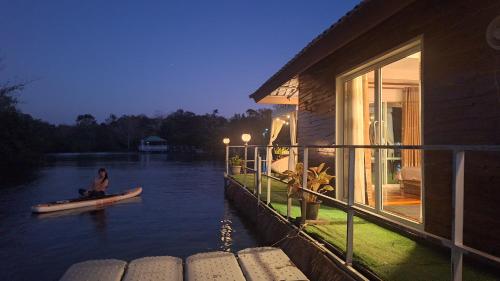een vrouw op een boot in het water naast een huis bij บ้านกลางโดม Baan Klang Dome in Ban Huai Hai