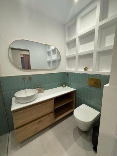 a bathroom with a sink and a toilet and a mirror at Cosy apartment with shared pool and garden in Athens