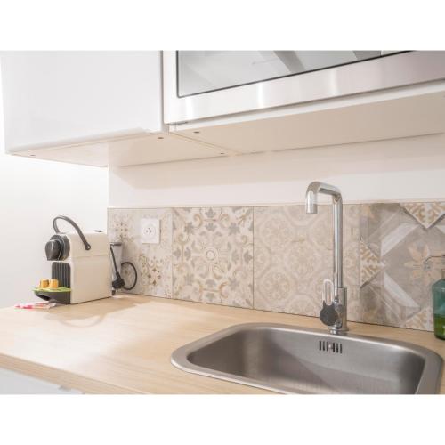 une cuisine avec un évier et un micro-ondes dans l'établissement Proche Théâtre, à Grasse