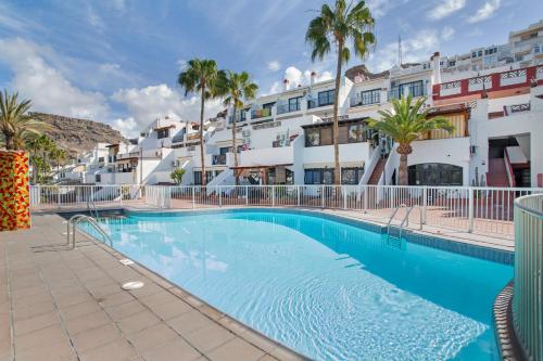 a swimming pool in front of a building with palm trees at Daniel House in Mogán