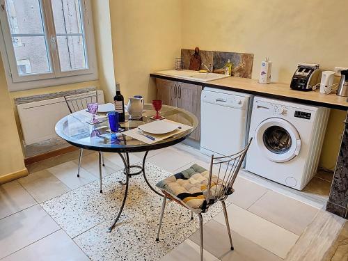 a kitchen with a table and a washing machine at Résidence Verdi - Appartements meublés en centre ville in Bédarieux