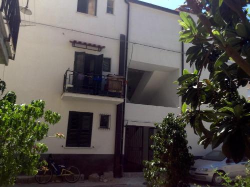 a white building with a balcony and a car parked in front at Fiordaliso in Caulonia Marina