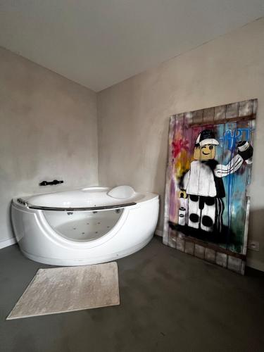 a bathroom with a toilet and a painting on the wall at La folie douce Jacuzzi et clim in Montauban