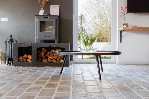 a living room with a fireplace and a table at Unieke landelijke woning met zwembad in Kranenburg
