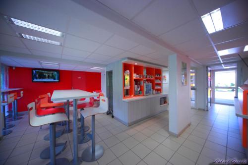 a restaurant with red walls and a table and chairs at Premiere Classe Ales - Anduze in Alès