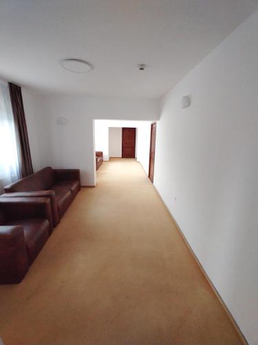 an empty room with a couch and a hallway at Pensiunea Bocca Del Rio in Gura Rîului