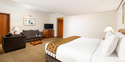 a hotel room with a bed and a living room at Aryaduta Menteng in Jakarta