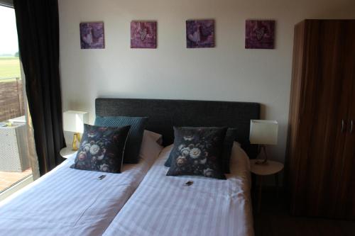a bedroom with two beds with pillows and a window at Bed & Breakfast Rheiderland in Ditzumerverlaat