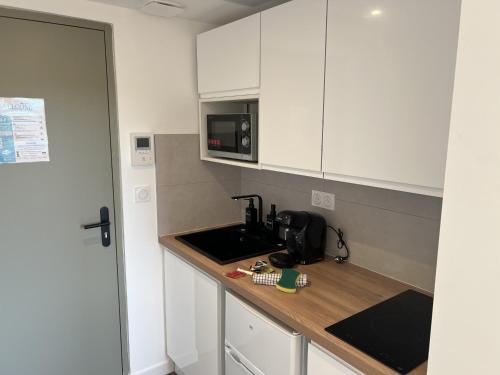 a kitchen with a sink and a microwave at Résidence Claire Roman in Valence