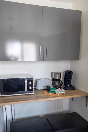 a kitchen counter with a microwave and appliances on it at Le Chez Moi Hyper Centre Parking 3mn Gare in Montigny-le-Bretonneux