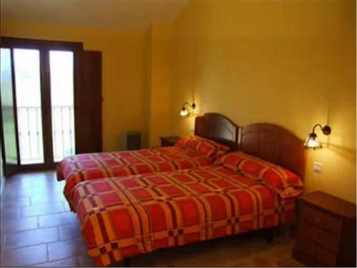 a bedroom with a bed with a red and orange blanket at La Venta Vieja de Langre in Langre