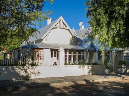 a white fence in front of a white house at KAROOWERF GUEST HOUSE in Cradock