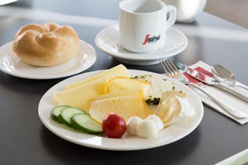 a table with two plates of cheese and a bagel at arte Hotel Krems in Krems an der Donau