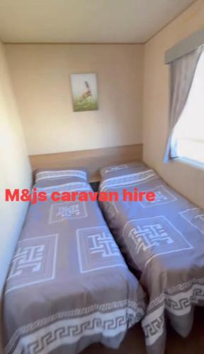two beds sitting next to each other in a room at M&js caravan hire in Kinmel Bay