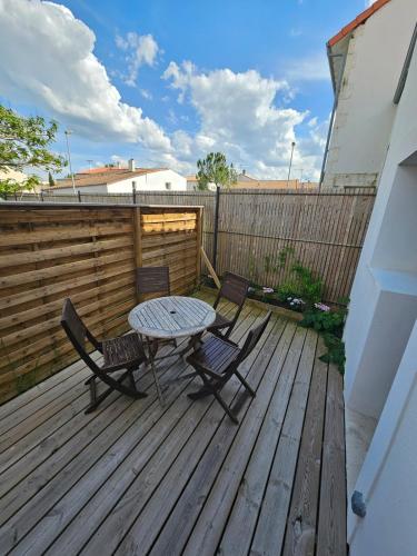 une terrasse en bois avec une table et des chaises. dans l'établissement Le 6 - B Saint Xandre, à Saint-Xandre