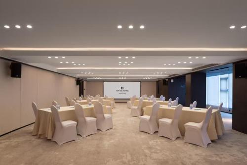 a conference room with white chairs and a screen at 中濠悦际酒店 深圳国际会展中心店 in Shenzhen