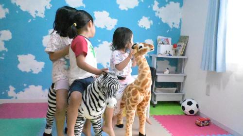 a group of children playing with stuffed giraffes and a zebra at Ko's HOUSE Shinmori7 in Osaka