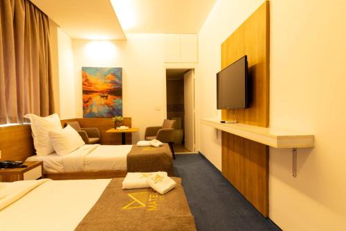 a hotel room with two beds and a flat screen tv at Mateus Hotel & Pool in Jounieh