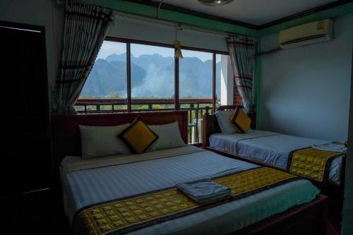 two beds in a room with a view of a mountain at Vang Vieng Mountain View Hotel in Vang Vieng